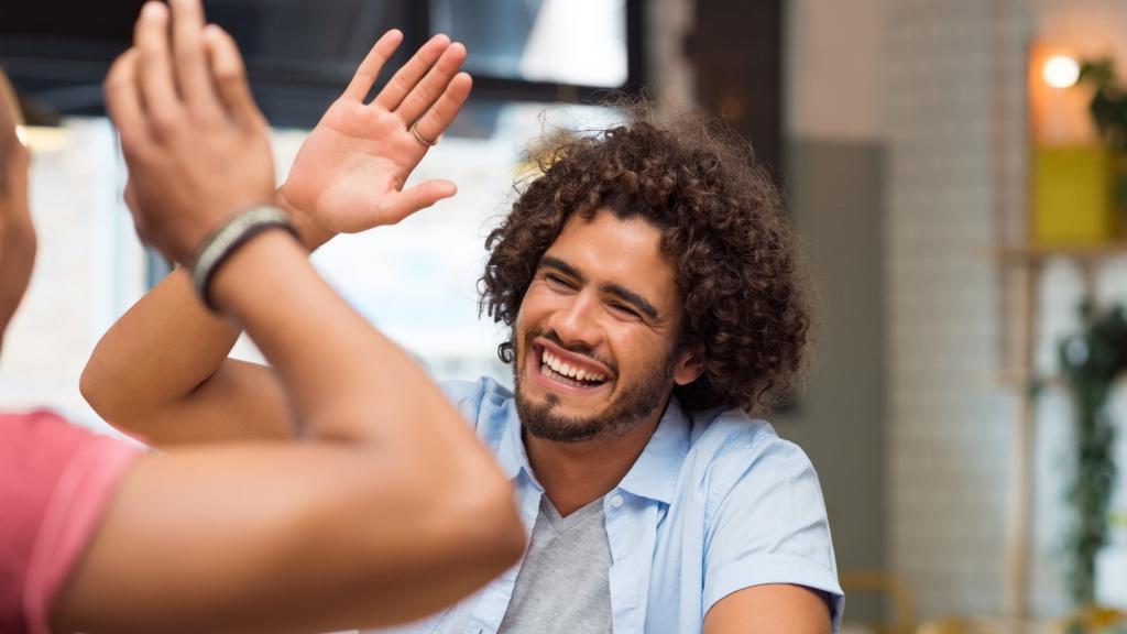 Smiling man receives a high five.